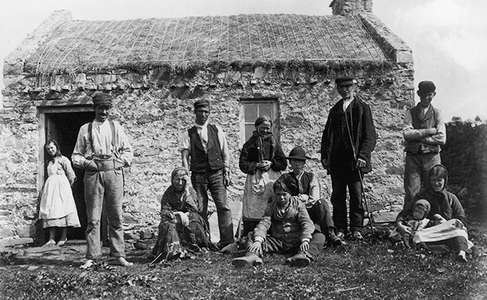 Vers 1900 : Des habitants de Gweedore, dans le comté de Donegal, devant leur petite ferme au toit de chaume. On remarquera les pieds nus d’une partie de la famille.