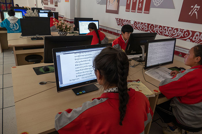 Travail sur ordinateur dans une école secondaire du Tibet. L’écran à gauche affiche un texte en caractères tibétains, l’écran à droite un texte en anglais. (Photo : A.E.)
