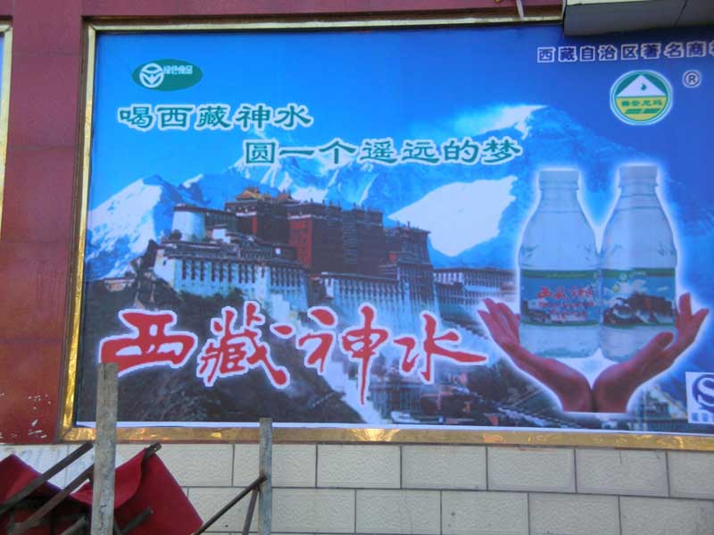 Publicité pour de l'eau minérale tibétaine dans une rue commerçantede Lhassa  (photo J.-P. Desimpelaere, 2008)