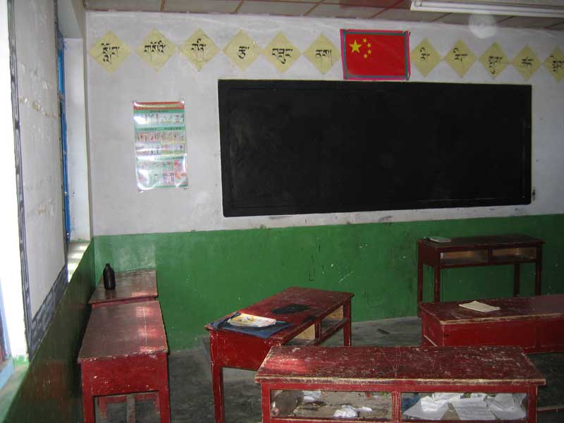 Dans un petite école de village au Qinghai en périodes de vacances (photo JPDes, 2005)... des lettres en tibétain au mur, à côté du drapeau chinois